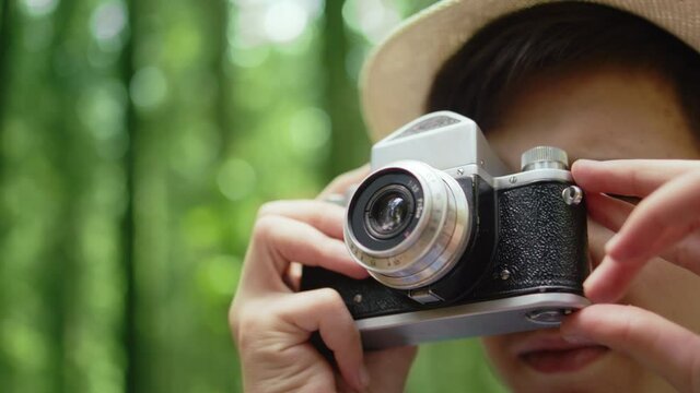 travel teen boy takes pictures in the forest with an old camera in summer, close up