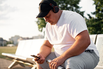 Fat man in sportswear sits on a bench