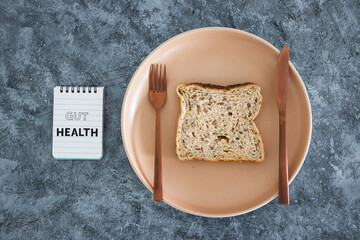 gut health notepad next to wholegrain multiseeds slice of bread on dining plate with fork and...