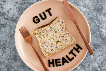 gut health text with wholegrain multiseeds slice of bread on dining plate with fork and knife,...