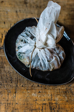 Papillote with marinated vegetables in a black bowl