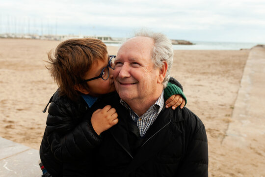 Grandson kissing his grandfather at the beach