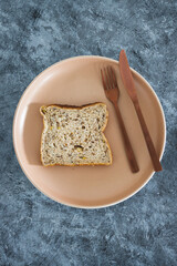 wholegrain multiseeds slice of bread on dining plate with fork and knife, dieting vs healthy nutrition and intuitive eating