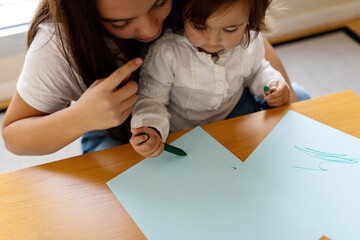 Nanny helping the baby girl to draw