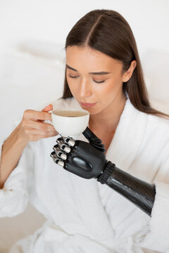 Girl with a prosthesis on her arm drinks coffee 