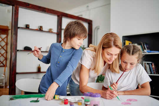 Woman helping child to create painting indoor
