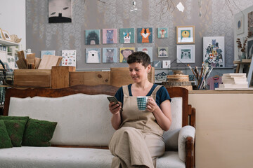 Successful Artist Smiling At Phone And Holding Cup 