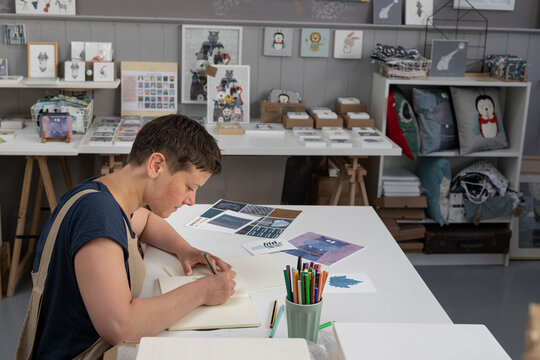 Close Up Of Illustrator Hand Drawing On Notebook