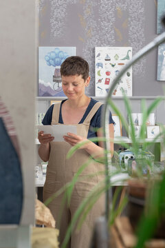 Young Illustrator Selecting Canvas To Hang On The Wall 