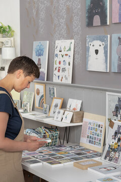 Young Illustrator Selecting Canvas To Hang On The Wall 