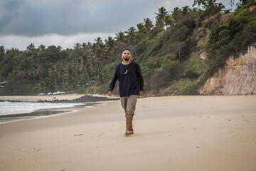 Young man of hippie appearance walking on a deserted beach.