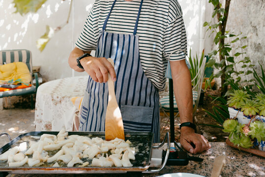 Unrecognizable man cooking seafood in outdoor griddle