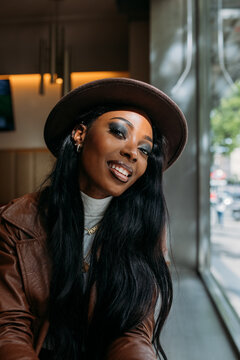 Happy black woman in leather coat and hat