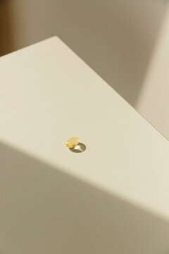 Yellow supplement pill on white desk 
