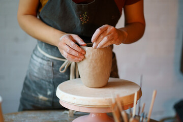 Focus on art and handicraft: cropped image of female concentrated sculpturing potter tableware in...