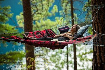 Woman resting in suspended hammock in nature