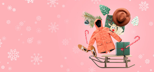 Sledges with Christmas gift, flying winter clothes and decorations on pink background with space for text