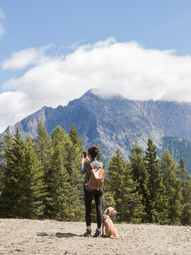 girl take a picture on mountain with dog 