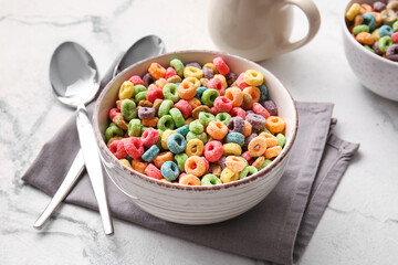 Bowl of colorful cereal rings on light background