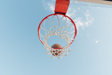 Basketball falling into basketball hoop. 