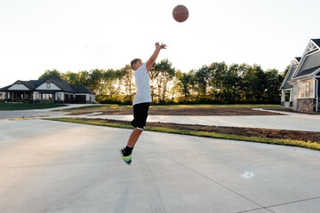 Side profile of a boy shooting the basketball. 