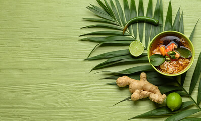 Bowl of spicy Thai soup on color wooden background