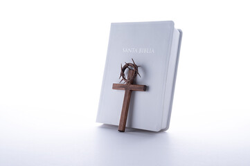 Crown of thorns, bible and wood cross on white background. Easter or Resurrection concept. He is...