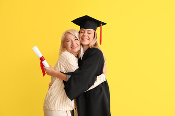 Happy female graduation student with her mother on color background