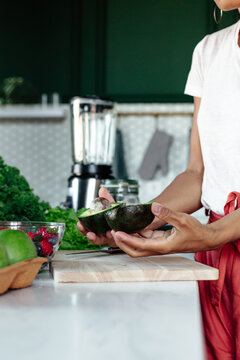 Anonymous black woman halving fresh avocado