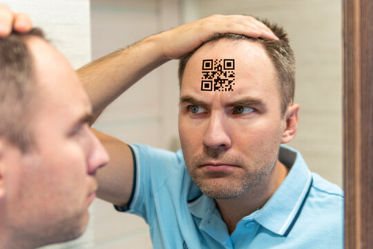 young man with a qr code on his forehead. A man with a stupid expression looks at his qr code on his head. The concept of chipping the population. global control and governance - Powered by Adobe