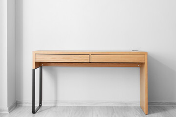 Empty wooden desk near light wall