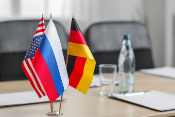 Flags of Russia, Germany and USA on table in conference room