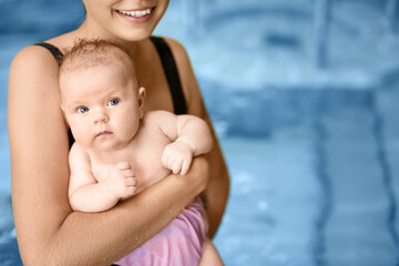 Cute baby with mother in swimming pool