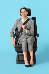 Young woman fastening in car seat on blue background