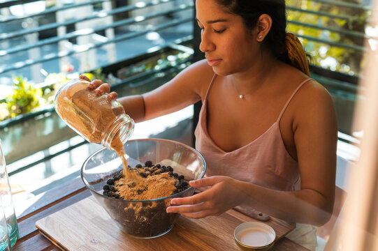 Female adding sugar to the mixture to make jam