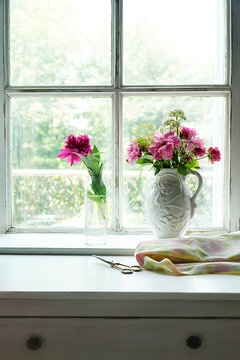 Pink roses in jugs on window sill