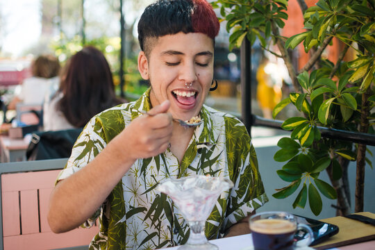 Latino trans man eating dessert outdoors