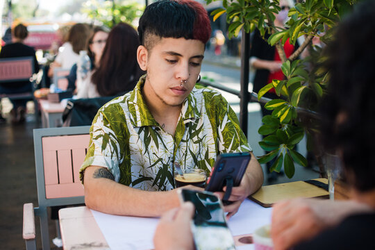 Latino gen z posting on social media at a restaurant