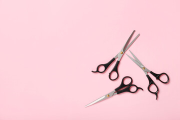 Scissors of hairdresser on color background, top view