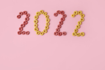 Figure 2022 made of cereal rings on pink background