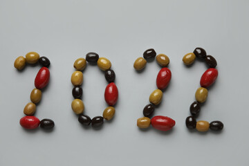 Figure 2022 made of different olives on grey background, closeup