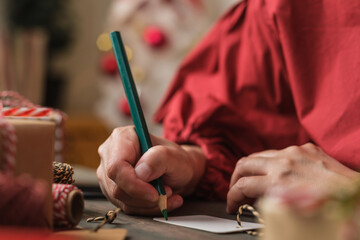 woman writing gift tag and attach to christmas present on wood table