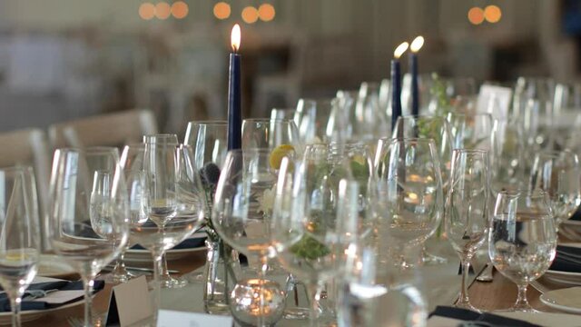 Slider shot of wedding dinner table with glasses and candles.