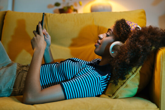 Black female browsing cellphone on couch