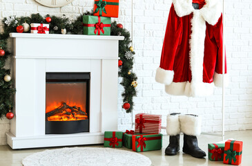 Fireplace, Christmas gifts, hanger with Santa suit and boots near white brick wall