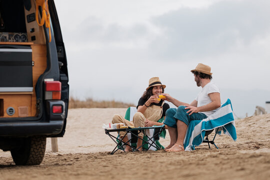 Couple relaxed on beach with caravan