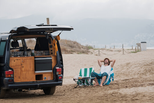 Man relaxing on beach with caravan