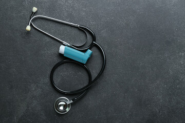 Asthma inhaler and stethoscope on dark background