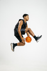 Black basketball player jumping with ball