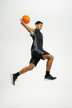 Black basketball player jumping with ball